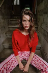 Jersey rojo de punto con escote en V pronunciado tanto en el delantero como en la espalda, mangas largas y diseño entallado en la cintura con caída acampanada.
