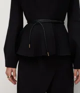 Cardigan de punto color negro con escote en V profundo, mangas largas y bajo con diseño peplum. Incluye un cinturón fino de material sintético con punteras metálicas para ajustar a la cintura.