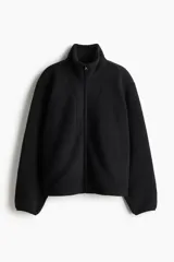 Campera deportiva de sherpa cálida y suave, color negro, con cuello elevado, cierre frontal y bolsillos laterales. Cuenta con corte holgado y elásticos en puños y bajo.