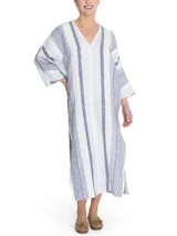 Túnica de corte amplio confeccionada en una mezcla de lino y algodón orgánico, con diseño a rayas verticales en tonos azul y blanco. Presenta escote en V con detalle desflecado, mangas tres cuartos y aberturas laterales en el ruedo.