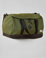 Bolso de viaje tipo duffel color verde oliva con base negra. Tiene doble asa de mano y correa de hombro ajustable. Presenta un bolsillo frontal con cierre y logo de la marca en etiqueta de goma.