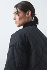 Campera tipo barn capitoneada de color marrón, con silueta corta y relajada. Presenta cuello de pana, cierre frontal con broches metálicos y bolsillos laterales funcionales.