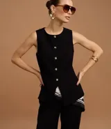 Chaleco negro de sastrería con cuello redondo, cierre frontal con botones dorados y bajo estructurado con recortes anatómicos.