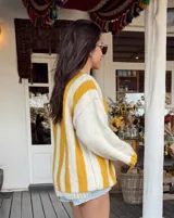 Sweater de lana color crema con rayas verticales anchas color amarillo mostaza, de corte holgado y cuello redondo. Tejido a mano.