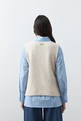 Chaleco tejido color marrón con bordados artesanales de motivos florales y geométricos en color crema. Presenta cuello redondo, cierre frontal con botones y diseño sin mangas.