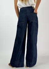 Pantalón de jean negro de corte ancho con bolsillos delanteros y traseros. Presenta una línea vertical blanca a lo largo de la pierna.