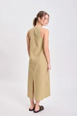 Vestido midi sin mangas, de corte recto y holgado, con cuello redondo. Presenta un estampado de rayas verticales finas en tonos amarillo claro y verde oliva/marrón.