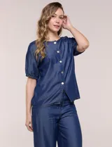 Blusa de calce relajado de lyocell en tono azul denim, con cuello a la base y cierre frontal de botones metálicos. Tiene mangas cortas abullonadas con puños elásticos.