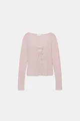 Chaqueta de punto color beige con escote en pico y manga larga, que incluye un top interior integrado con detalle de encaje a tono. Cierre frontal mediante botones.