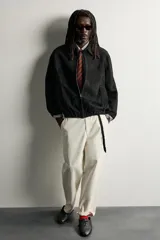 Cazadora de piel con acabado serraje de corte relaxed fit, color negro, con cuello solapa, bolsillos de vivo en la cadera, bajo elástico y cierre frontal con cremallera de doble dirección. Colección especial Aaron Levine x ZARA.