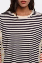 Remera manga larga oversize de corte relajado, confeccionada en 100% algodón orgánico con cuello redondo. Presenta un diseño de rayas horizontales en combinación de tonos azul marino, beige, blanco y detalles en rojo.