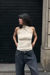 Top ajustado de tejido acanalado color crema, con cuello perkins y sisa adornada con aplicación de encaje a tono.