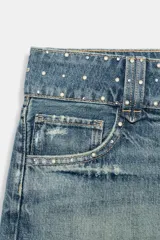 Shorts de denim de tiro bajo con cinco bolsillos, detalle de tachas, aplicación de brillos, bajo deshilachado y cierre frontal con cremallera y botones metálicos.