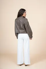 Chaqueta marrón oliva de cuero sintético, corte recto, cuello redondo y cierre frontal con cremallera. Tiene bolsillos con solapa en el pecho y mangas largas con puños abullonados.