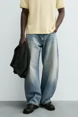 Jeans de hombre, corte balloon fit, tiro medio, confeccionados en denim rígido de algodón. Presentan un efecto lavado con un marcado degradado vertical, cinco bolsillos y cierre frontal con cremallera y botón.
