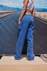 Pantalón de jean azul de corte babucha, tiro medio, con elástico en la cintura, bolsillos delanteros y logo bordado en amarillo en la pierna derecha.