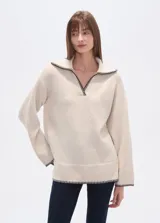 Sweater negro holgado con cuello en V y ribete en color crema en cuello, puños y ruedo.