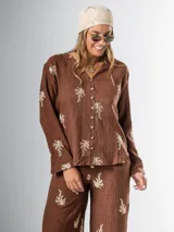 Conjunto de camisa y pantalón marrón chocolate con bordados en hilo crudo. El pantalón lleva elástico en la cintura.