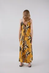 Vestido largo amarillo con estampado de hojas de palmera en blanco y negro, con breteles finos y botones en el frente.