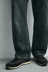 Zapatilla de estilo retro con cordones, confeccionada en una combinación de materiales textiles y piezas de cuero con acabado serraje. Presenta una suela dentada en contraste de color.