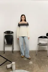 Sweater de punto color crudo con diseño de guardas geométricas en tonos negro, gris y beige en la parte superior.