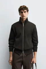 Chaqueta regular fit de tejido técnico interlock de algodón elástico, color azul marino. Presenta cuello subido, manga larga, bolsillos de vivo en la cadera, acabados en rib y cierre frontal con cremallera.