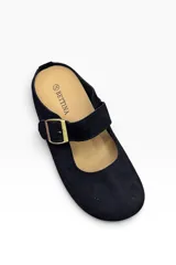 Zueco tipo bailarina de gamuza color camel, con diseño cerrado en la parte delantera, talón descubierto y una tira con hebilla metálica ajustable en el empeine.