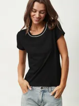 Remera negra de corte clásico con cuello redondo ribeteado con pequeñas perlas blancas.