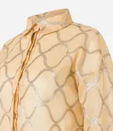 Camisa color dorado con estampado geométrico plateado, de manga larga con puños abotonados, cuello camisero y cierre frontal con botones ocultos.