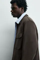 Sobrecamisa relaxed fit color beige con tejido elástico, cuello solapa, manga larga con puños abotonados, bolsillos de plastrón con solapa en el pecho, bolsillos laterales de vivo en la cadera y cierre frontal de botones.