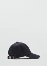 Gorro tipo gorra de visera confeccionado en denim de algodón oscuro, con mensaje bordado y cierre regulable con hebilla metálica.