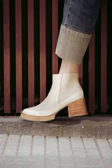 Botín de cuero color beige con puntera charolada, cierre lateral con cremallera y tacón ancho de madera.