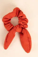 Gomita de pelo tipo scrunchie color naranja, con moño.