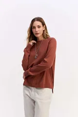 Sweater de tejido liviano color terracota, con cuello redondo, mangas largas y calce relajado. Presenta una costura vertical central en el frente y terminaciones en rib en puños y ruedo.
