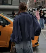 Chaqueta tipo bomber de calce holgado y silueta relajada, confeccionada en gamuza color azul marino. Presenta cuello camisero, cierre frontal oculto y mangas amplias con puños rectos.