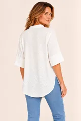 Blusa blanca de corte recto y holgado, con cuello camisero y escote en V. Cuenta con mangas cortas amplias y diseño minimalista.