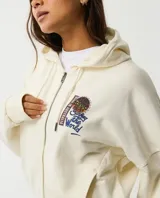 Canguro color marfil con capucha y cierre frontal, con gran estampado multicolor en la espalda que incluye las leyendas 'Born in Australia' y 'Surfing the World'.