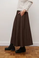 Falda larga de jean color azul oscuro con corte evasé y costuras con pespuntes a contratono. Presenta una cintura elástica para mayor comodidad.