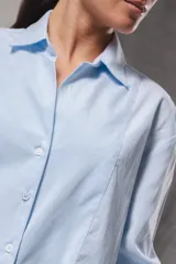 Camisa oversize de color celeste con un sutil diseño a rayas verticales blancas, manga larga y cuello camisero clásico.