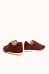 Zapatilla de gamuza color bordó con cordones bicolores, interior de cuero vacuno y suela de caucho blanca y beige.