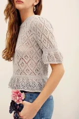 Sweater gris de tejido calado, con cuello redondo y mangas cortas abullonadas con puños elastizados.