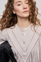 Blusa celeste de manga 3/4 con cuello mao, botonadura frontal y detalles calados en V con frunces. Presenta mangas con volumen y silueta fluida.