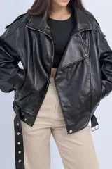 Campera estilo biker de cuero sintético negro, con cierre frontal, cuello solapa y cinturón ajustable en la cintura.