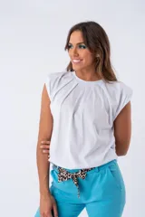 Remera blanca de algodón elastizado con hombreras y pliegues en el frente.