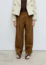 Pantalon de corte wide leg en color marrón, confeccionado en mezcla de algodón y lyocell. Presenta tiro medio, cierre frontal con cremallera y botón, trabillas para cinturón, bolsillos laterales y pinzas delanteras que aportan estructura.