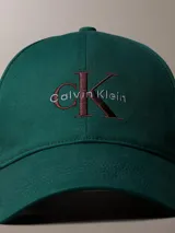 Gorra de béisbol de algodón color verde con visera curva y cierre ajustable en la parte posterior. Presenta el logo de la marca bordado en el frente en tonos contrastantes.