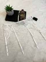 Portaligas de encaje blanco con tiras ajustables y broches metálicos para sujetar medias.