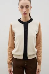 Saco de punto con cuello redondo y cierre frontal de botones. Presenta un diseño tricolor con cuerpo en color crema, tapeta de botones y cuello en negro, y mangas en color tostado.