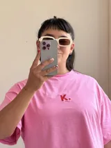 Remera rosa de corte cuadrado con logo bordado en rojo.