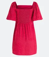 Vestido corto rojo con lunares blancos, escote cuadrado, mangas cortas abullonadas y abertura lateral en la falda.